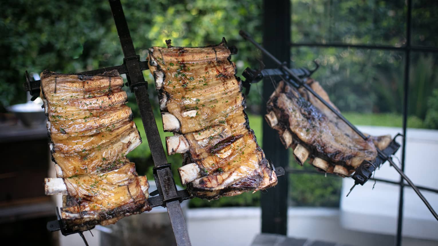 Several racks of ribs roasting over a fire.