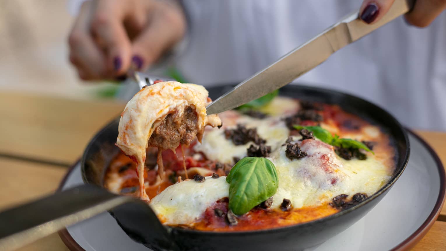 A braised short rib ravioli being cut into by a chef. 