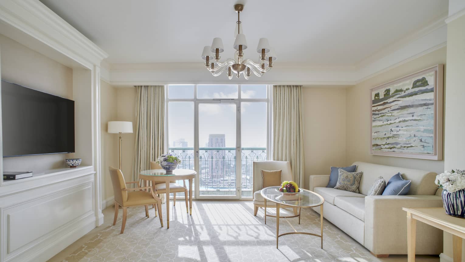 Hotel suite living room with beige sofa, gold and glass coffee table, built-in entertainment centre