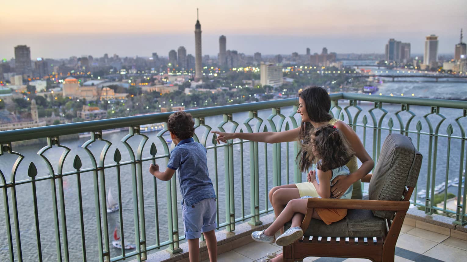 Woman seated with a young girl and beside a young boy standing, overlooking the Nile River and Cairo