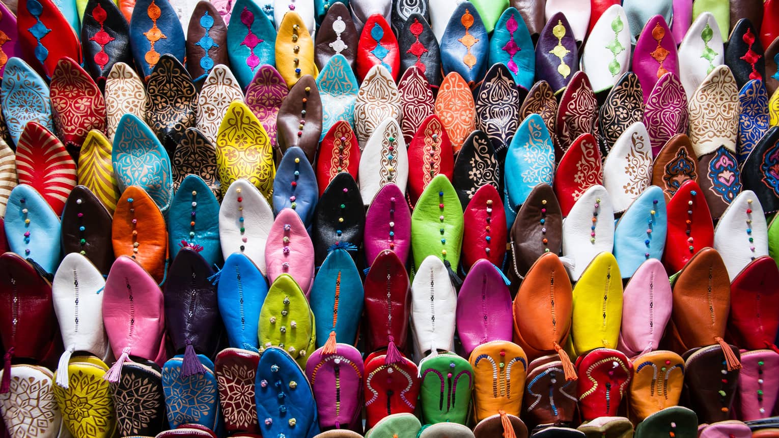 Rows of colourful beaded Oriental shoes in market 