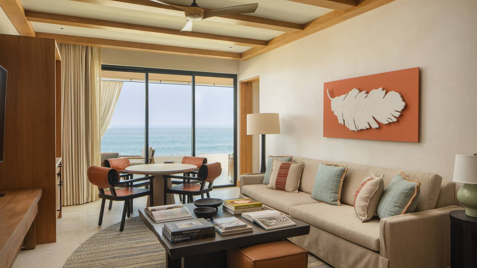 Luxury casita living room with sofa, large square coffee table, dining table with four chairs and oceanfront terrace at Four Seasons Resort Cabo San Lucas at Cabo Del Sol