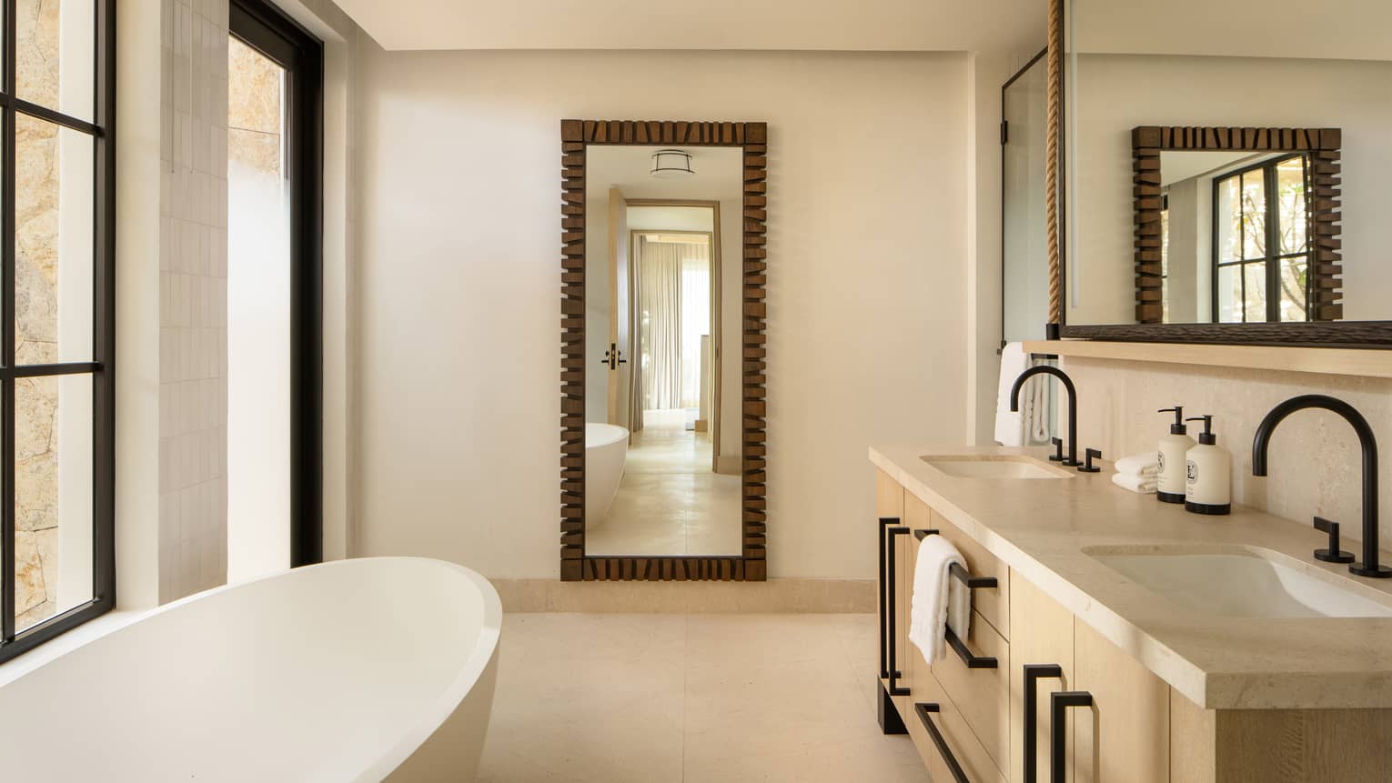 Luxury resort bathroom with double vanity and standalone oval tub, and a floor-length mirror
