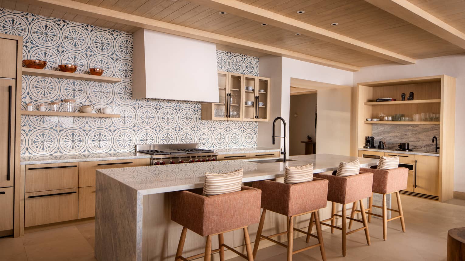 Luxury villa kitchen with mosaic tiled wall and island with four bar chairs at Four Seasons Resort Cabo San Lucas at Cabo Del Sol