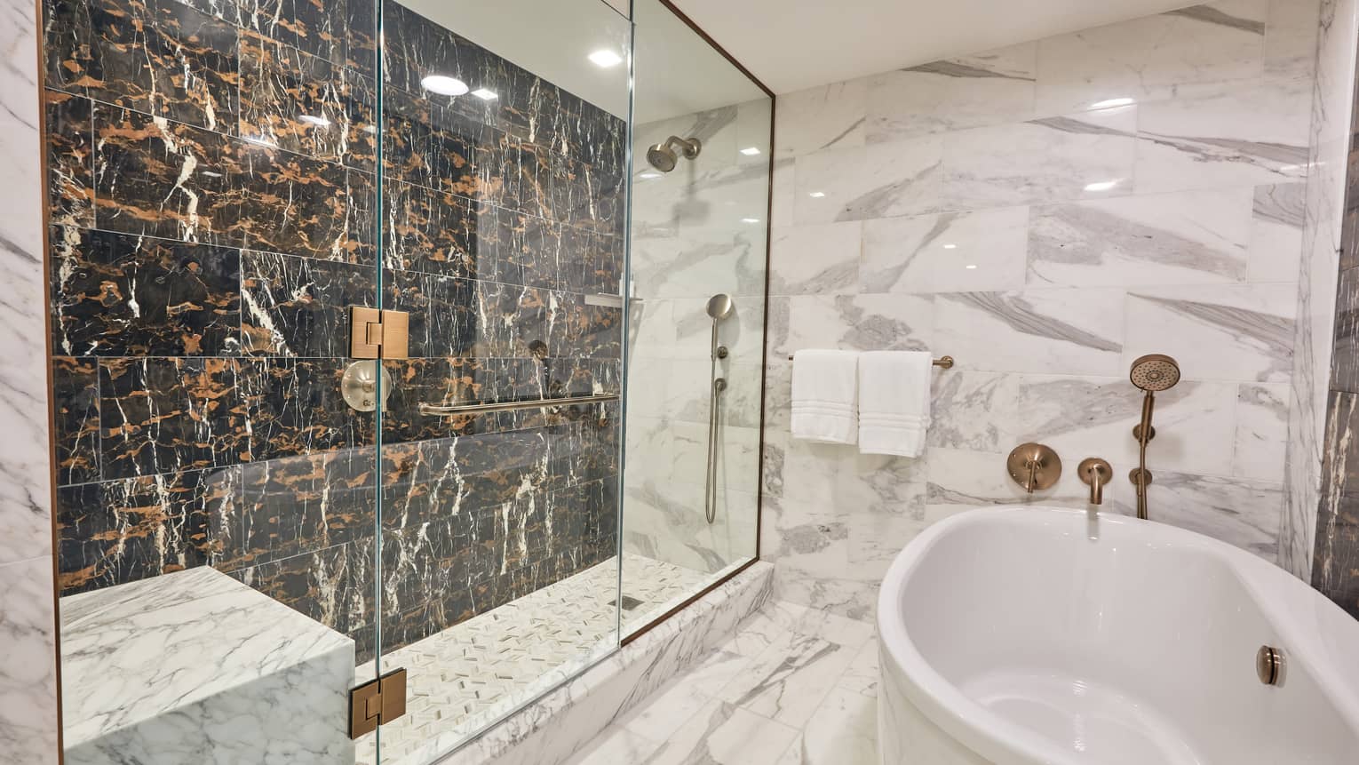 Marble bathroom with free-standing white tub, and walk-in shower with a black marble accent wall