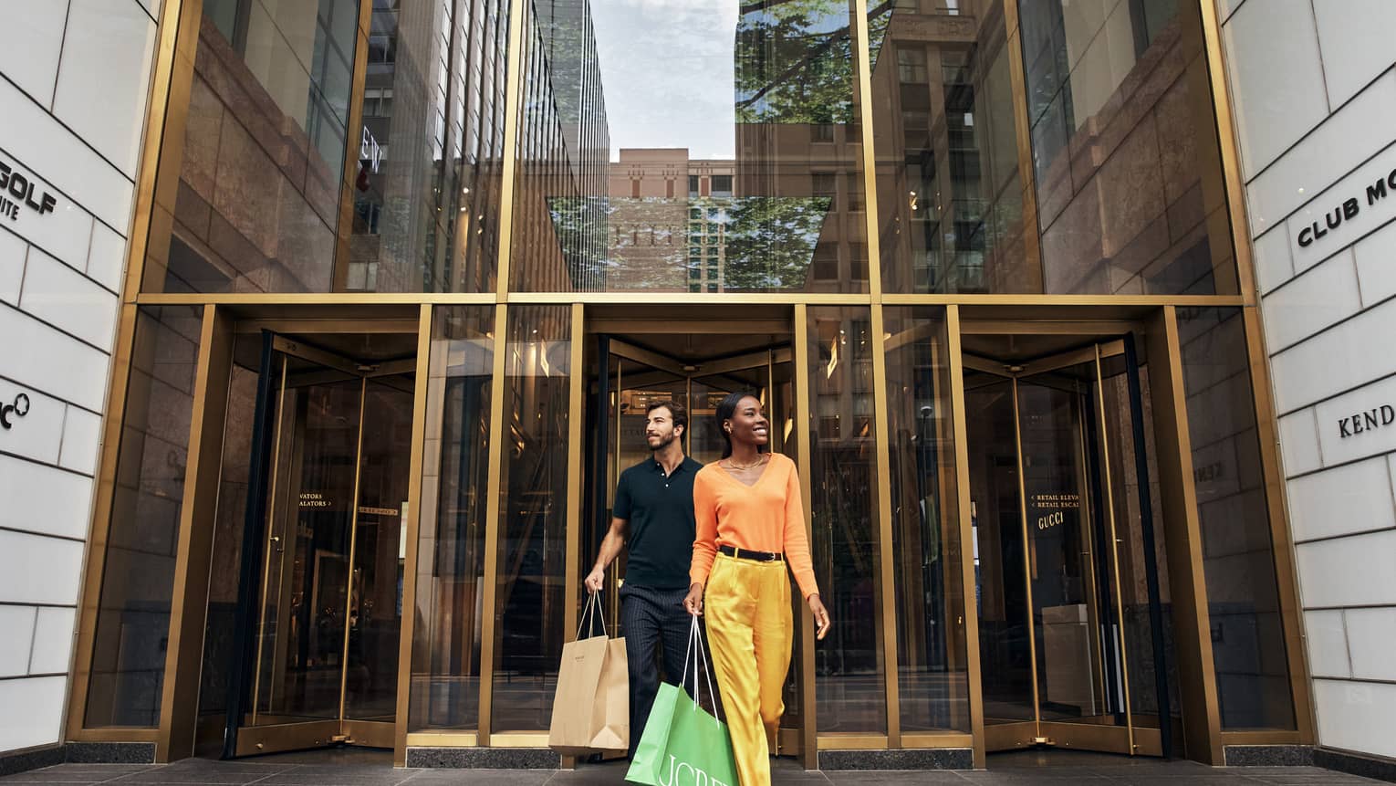 A man and woman walking out of a store with shopping bags.