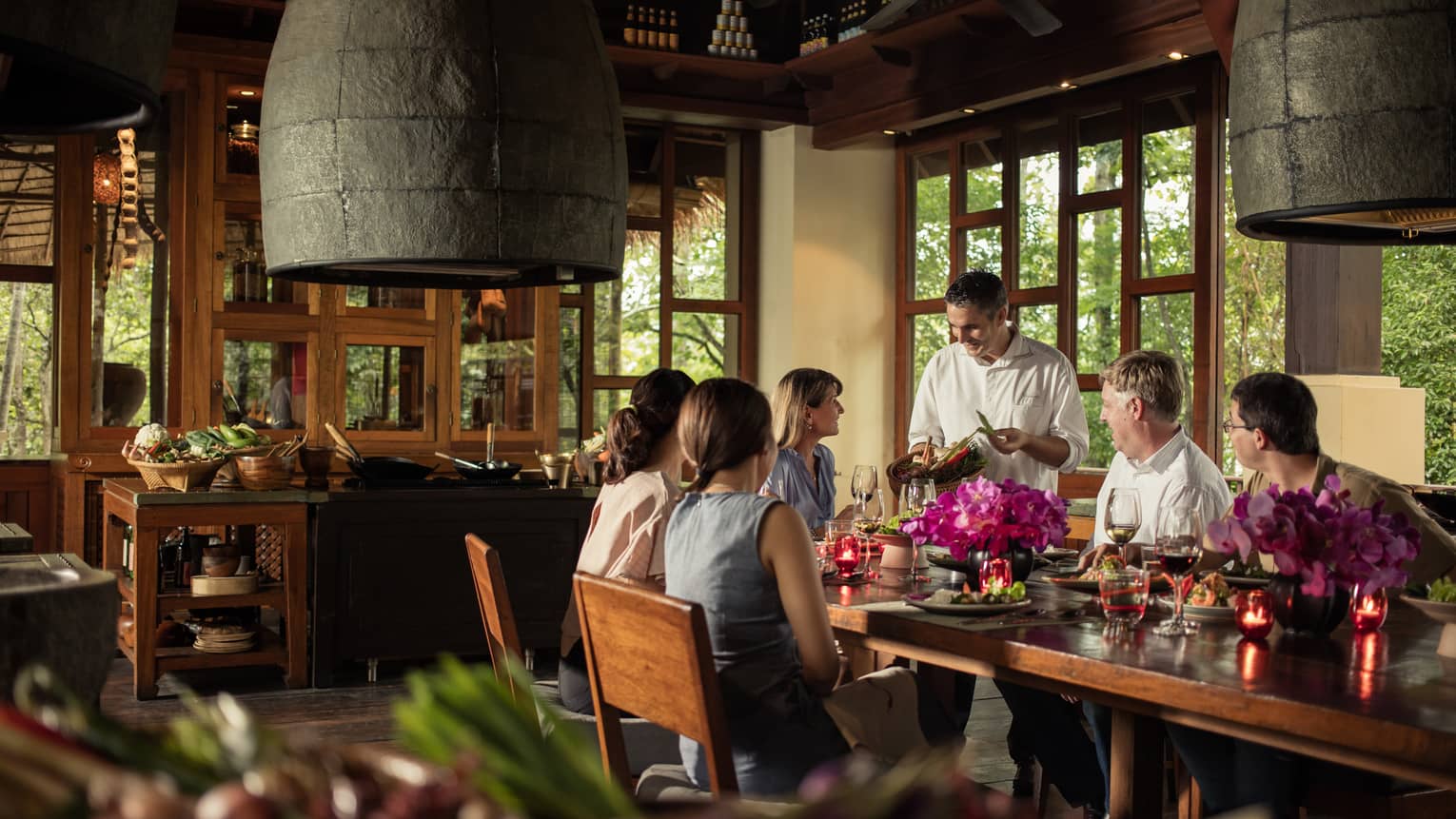 Chef presents basket with fresh hot peppers to guests at large private dining table