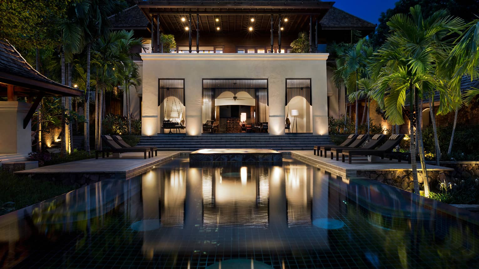 Large Four-Bedroom Residence Villa at night with lights, outdoor pool and palms 