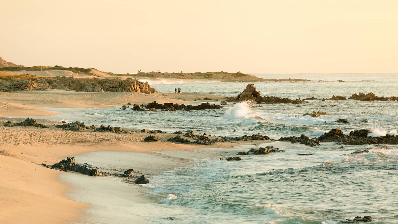 waves breaking on rocks and crashing on a sandy beach