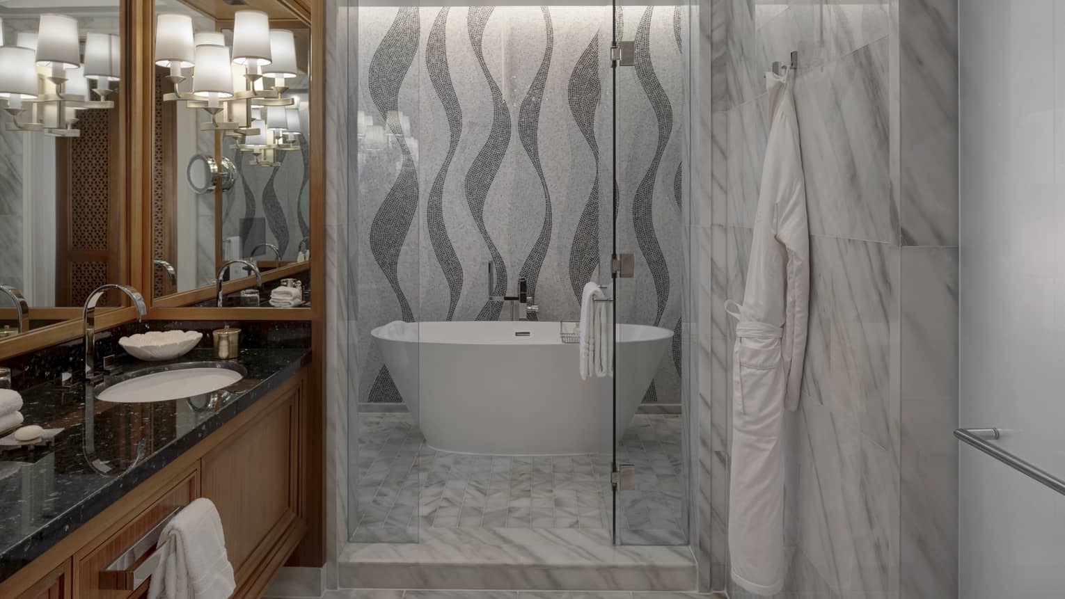 Bathroom with grey and white mosaic tile wall, white tub