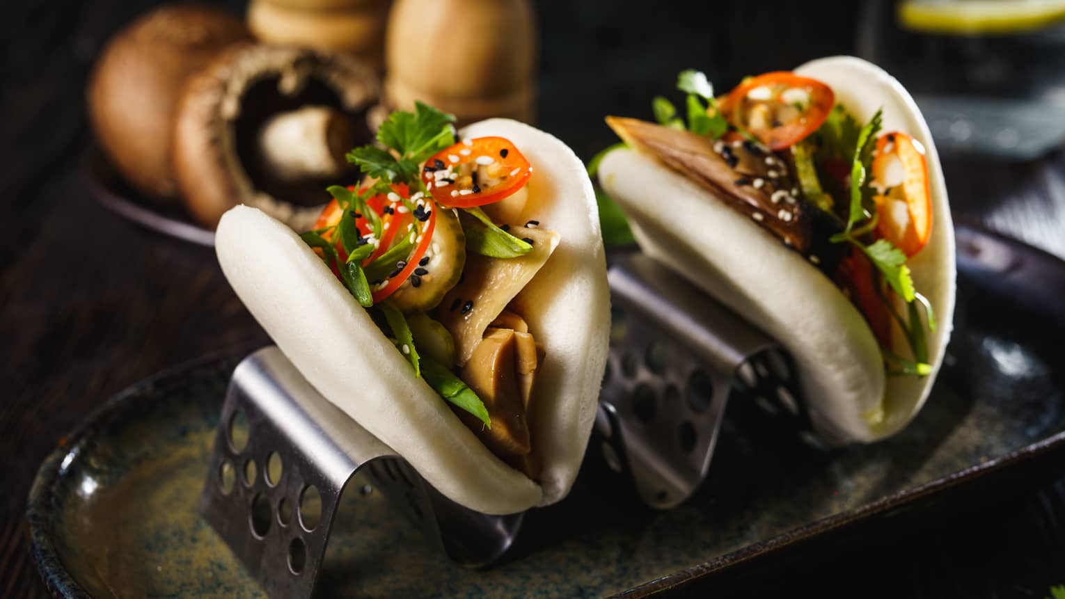 Two bao buns filled with tomatoes, mushrooms and greens.