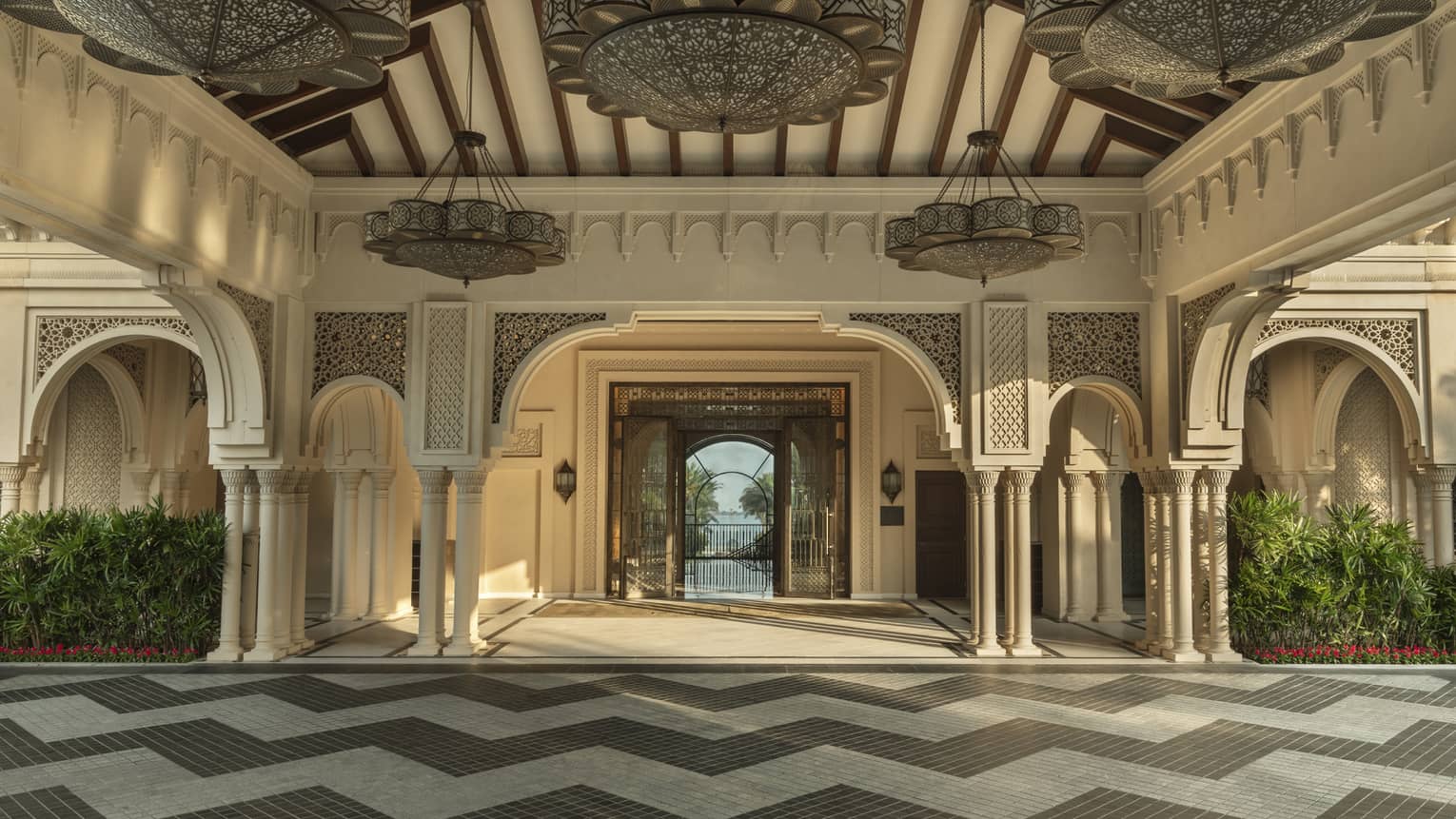 A grand hotel entrance with columns, arches and decorative lighting and tile surfaces