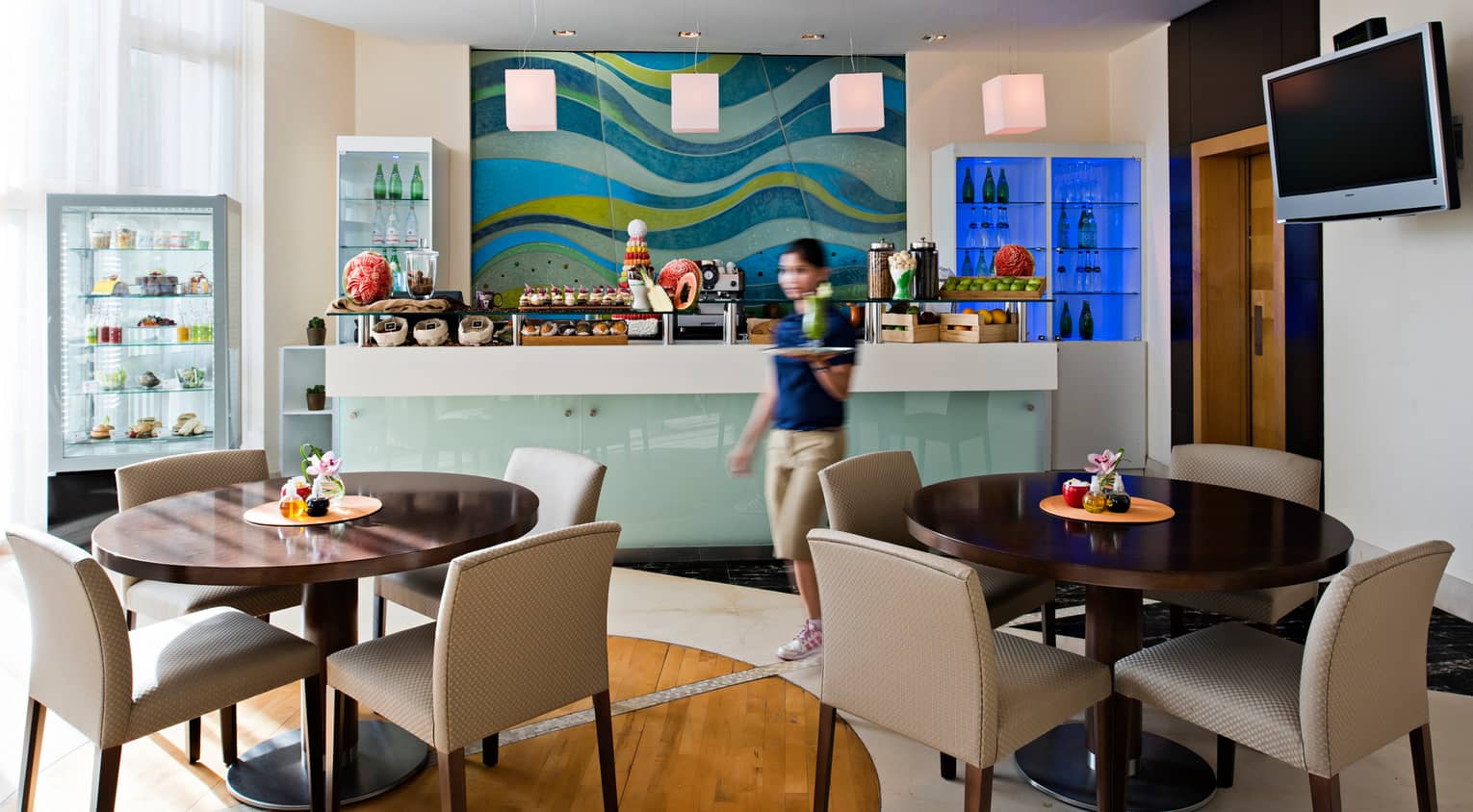 Server walks past dessert counter in bright Après Spa Café dining room