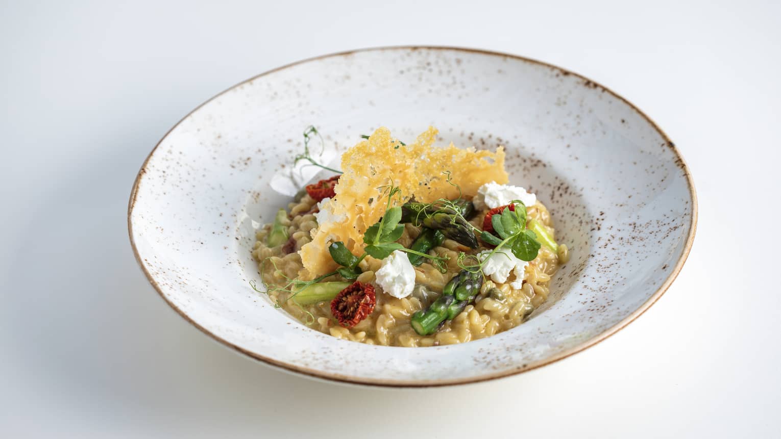 A grey bowl with vegetables and grains in it.
