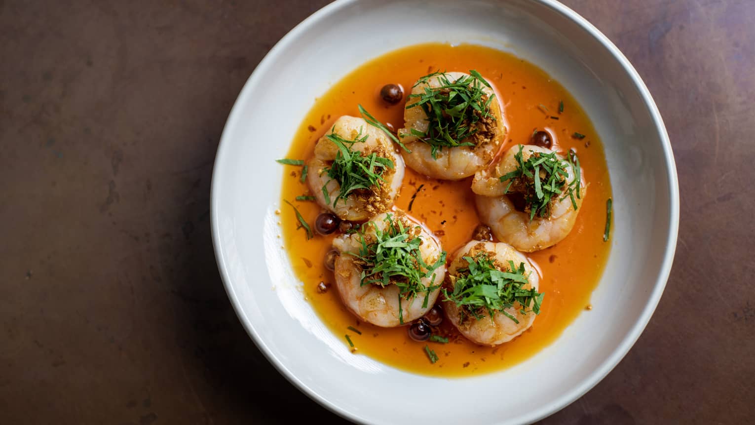 Sizzling Shrimp served with garlic oil and pepin chili on a round white plate