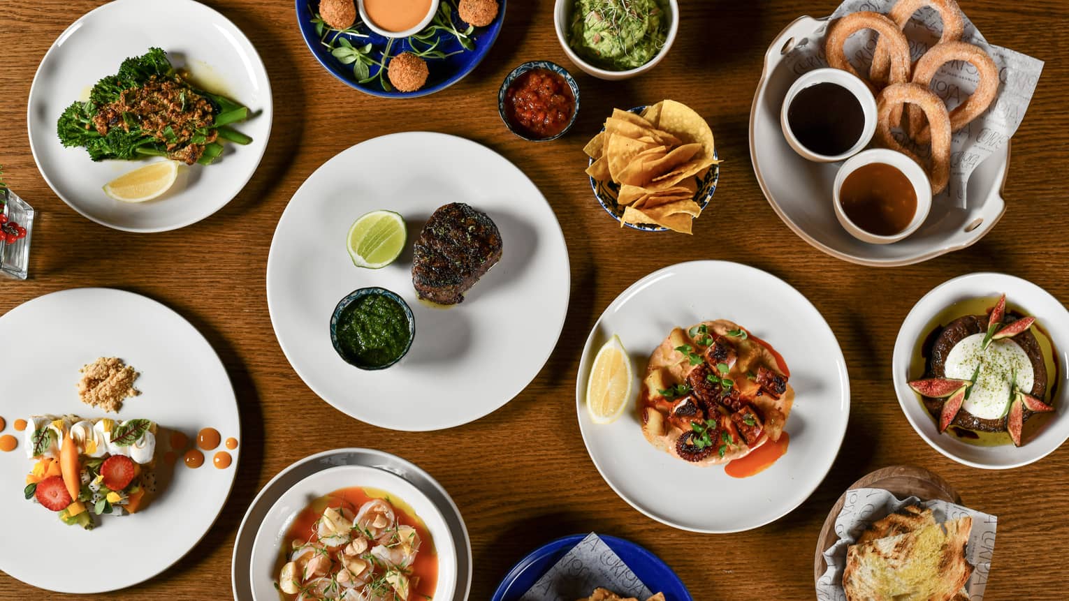 An overhead view of a wooden table filled a variety of dishes and bowls of food