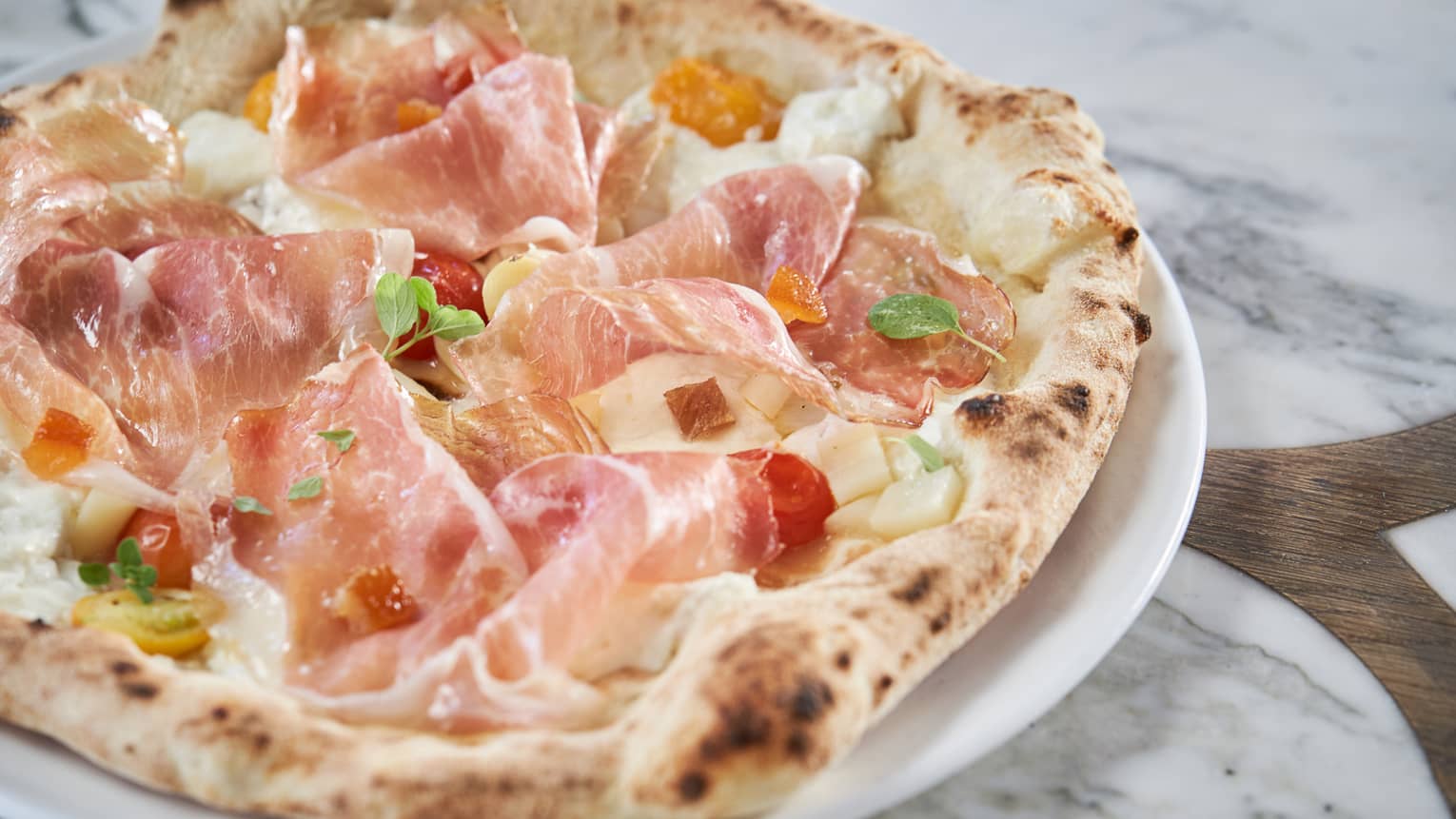 A signature pizza with prosciutto, cherry tomatoes and apricot 