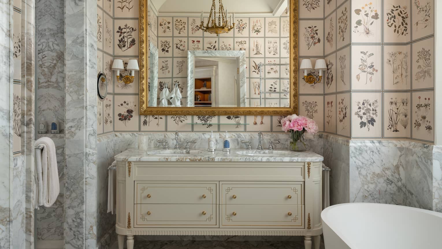 Hotel suite bathroom, featuring floral tiles on the walls, a standalone tub, separate shower and double dresser vanity