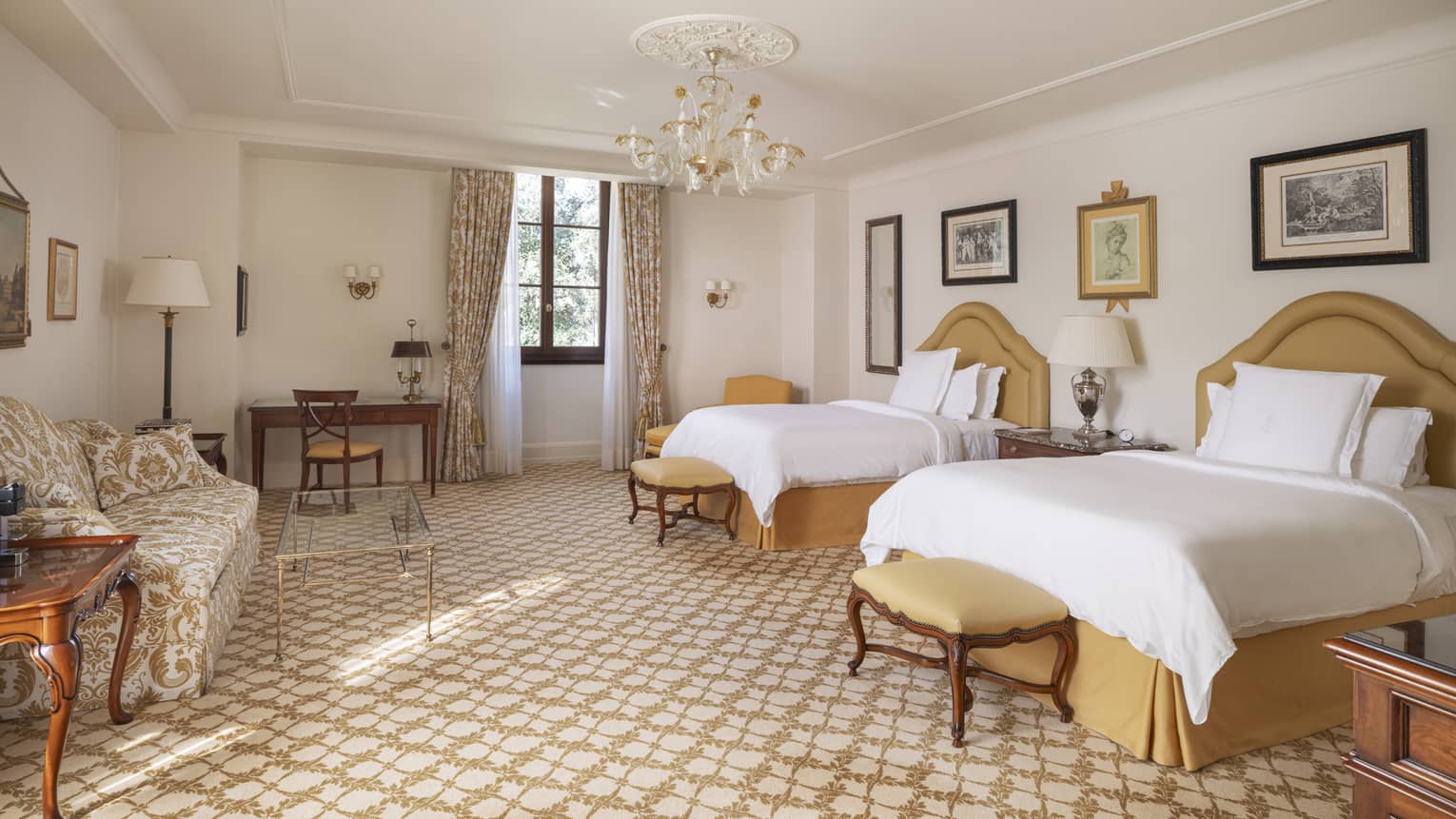 Elegant hotel room with two beds, chandelier, sofa and desk