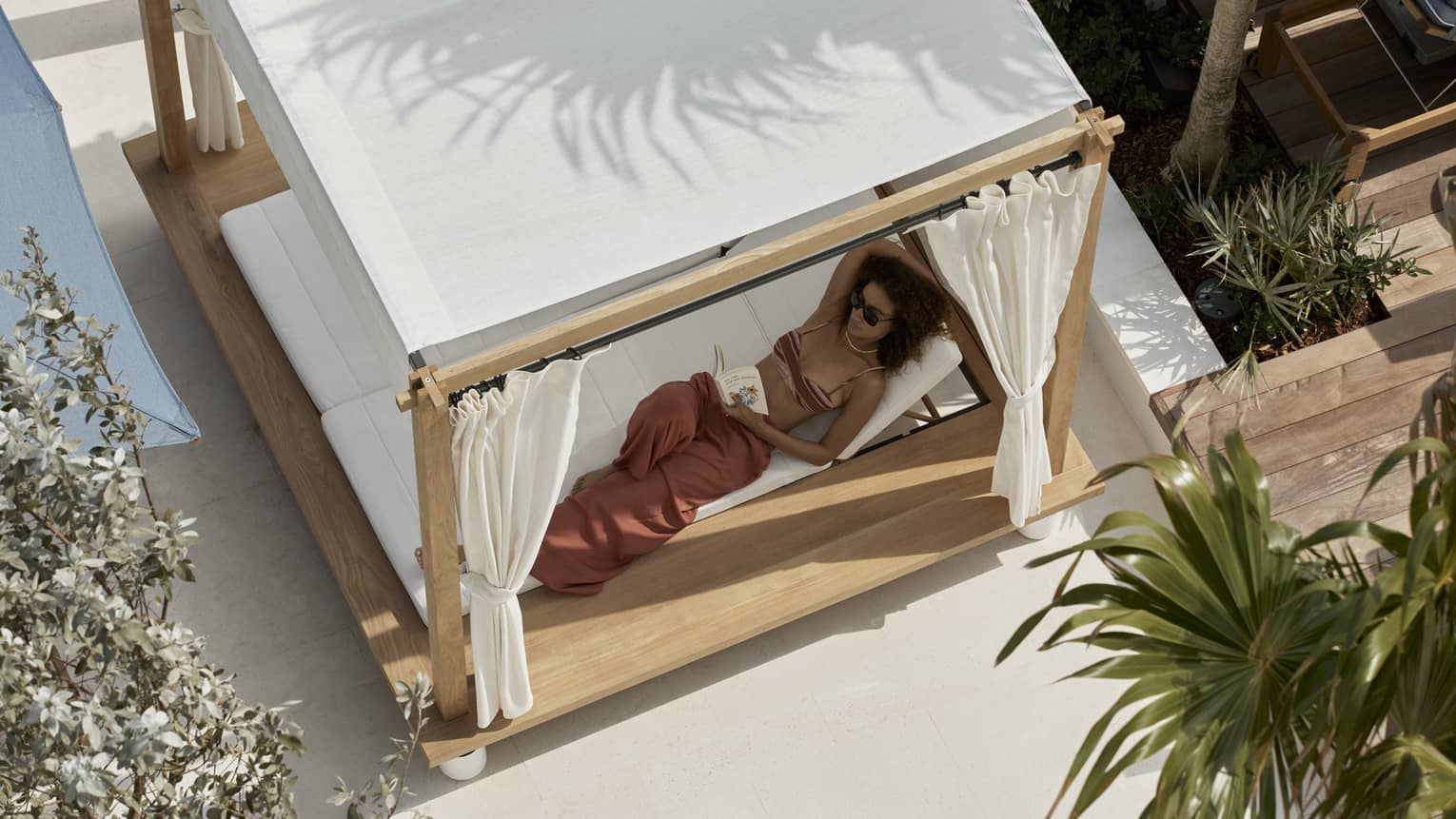 Aerial view of woman lounging in a covered poolside daybed