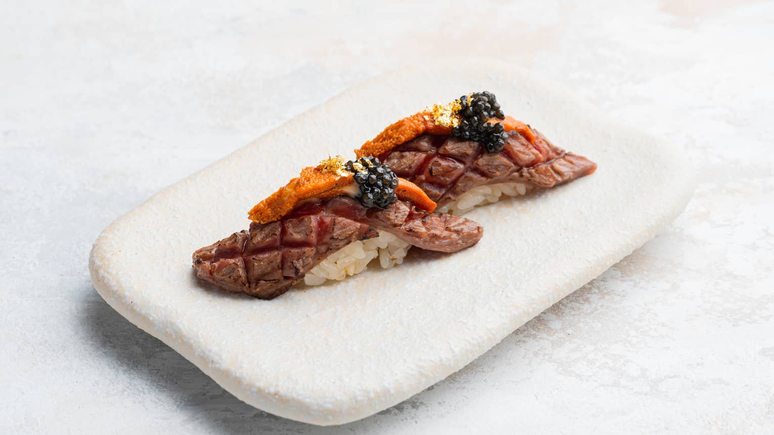 Wagyu, Sea Urchin and Caviar Nigiri on rectangular white dish