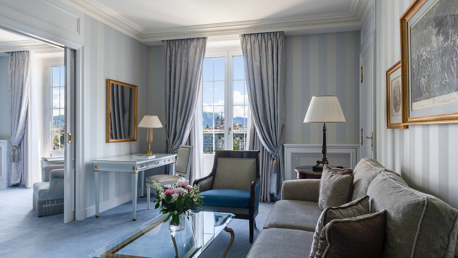 Four Seasons executive suite with striped wallpaper, a plush sofa, glass coffee table, armchair, desk and large windows offering city and mountain views