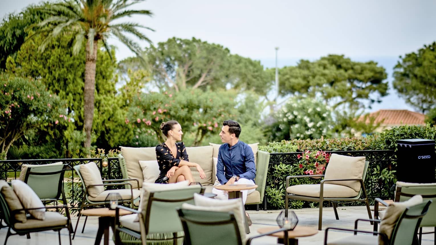 Le Bar terrace with couple seated on beige settee, light-green chairs and beige cushions