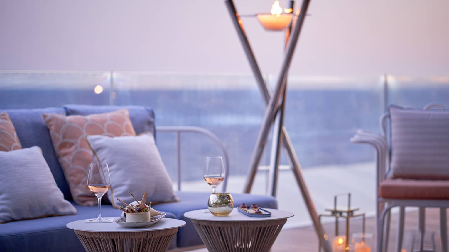 Club Dauphin terrace, blue love seats, orange pillows, candles, torch, sea view at sunset