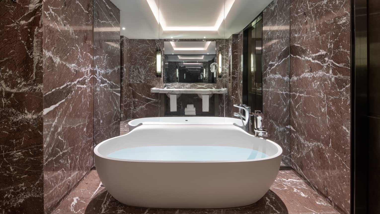 Guest bathroom with chocolate marble, mirrored wall, large soaking tub