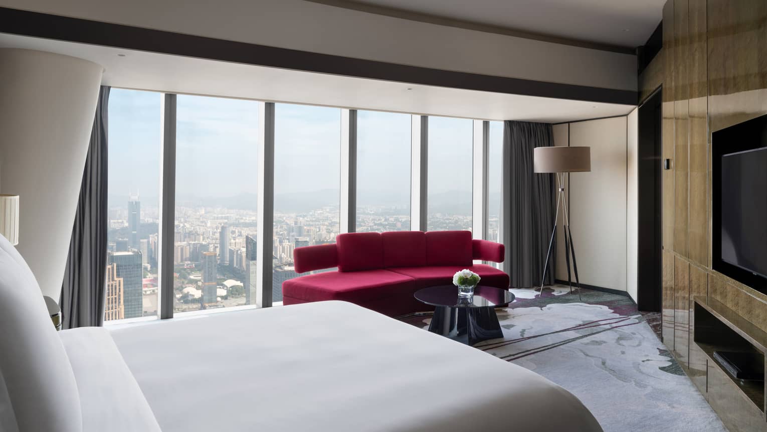 Deluxe King Suite City View Room with red sofa and floor-to-ceiling windows