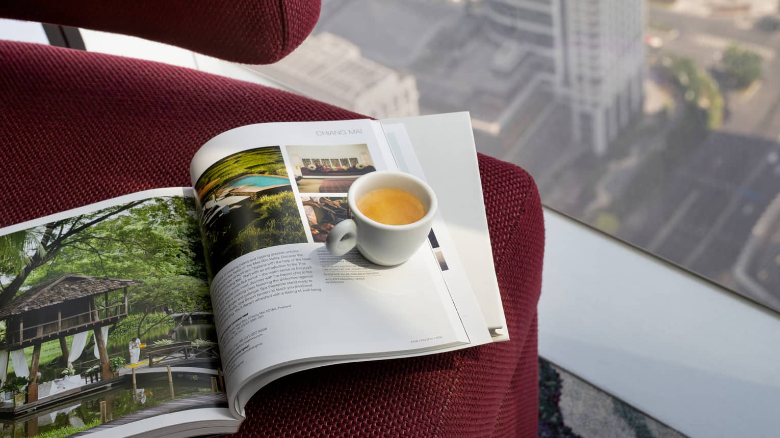 Four Seasons magazine and mug of tea sit on red chair at window