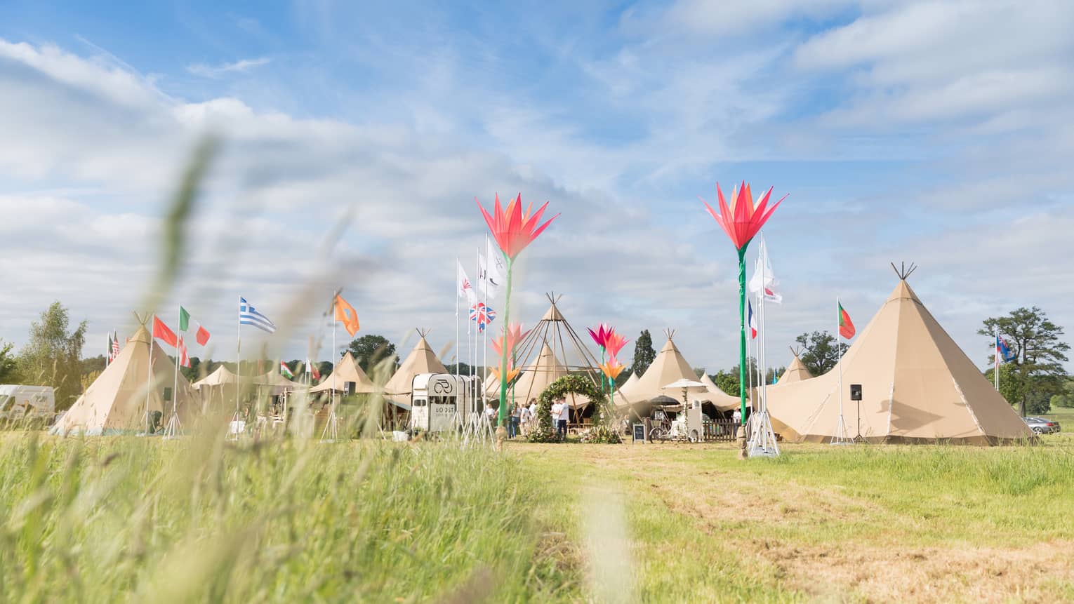 An outdoor function including tepees in a grass field