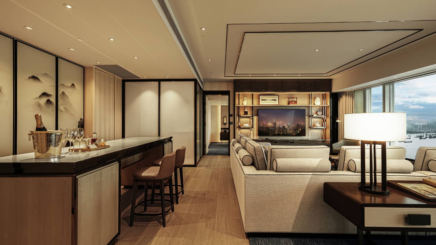 Contemporary hotel suite with sectional sofa, bar counter, wood floors and recessed lighting