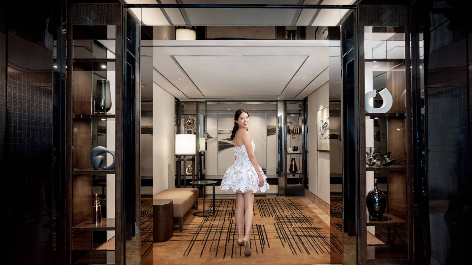 Woman looks back as she walks through hotel suite