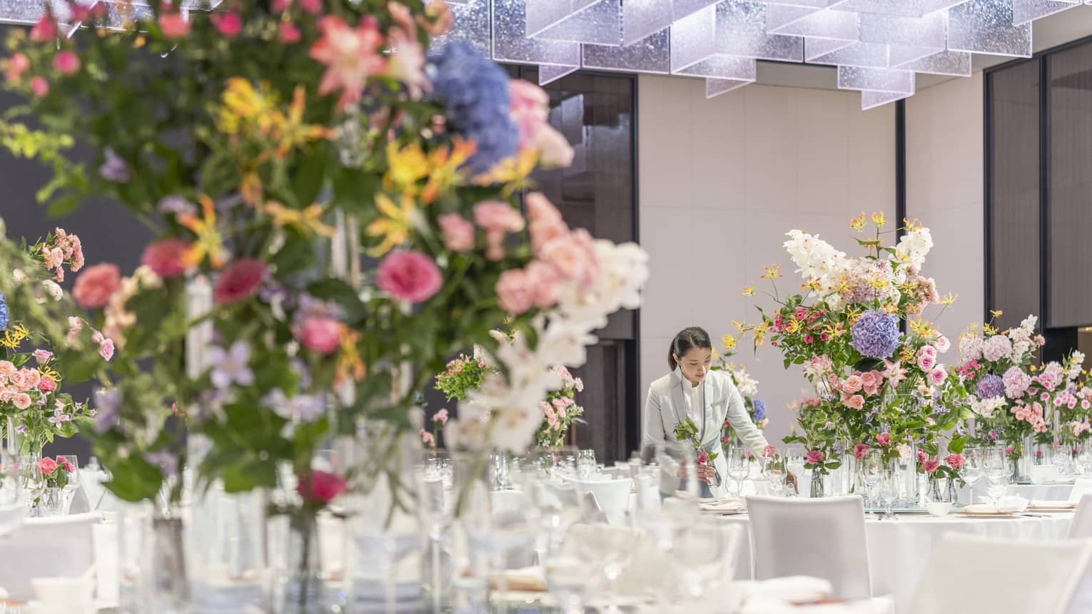 A ballroom set for an event with banquet tables featuring large colourful floral arrangements