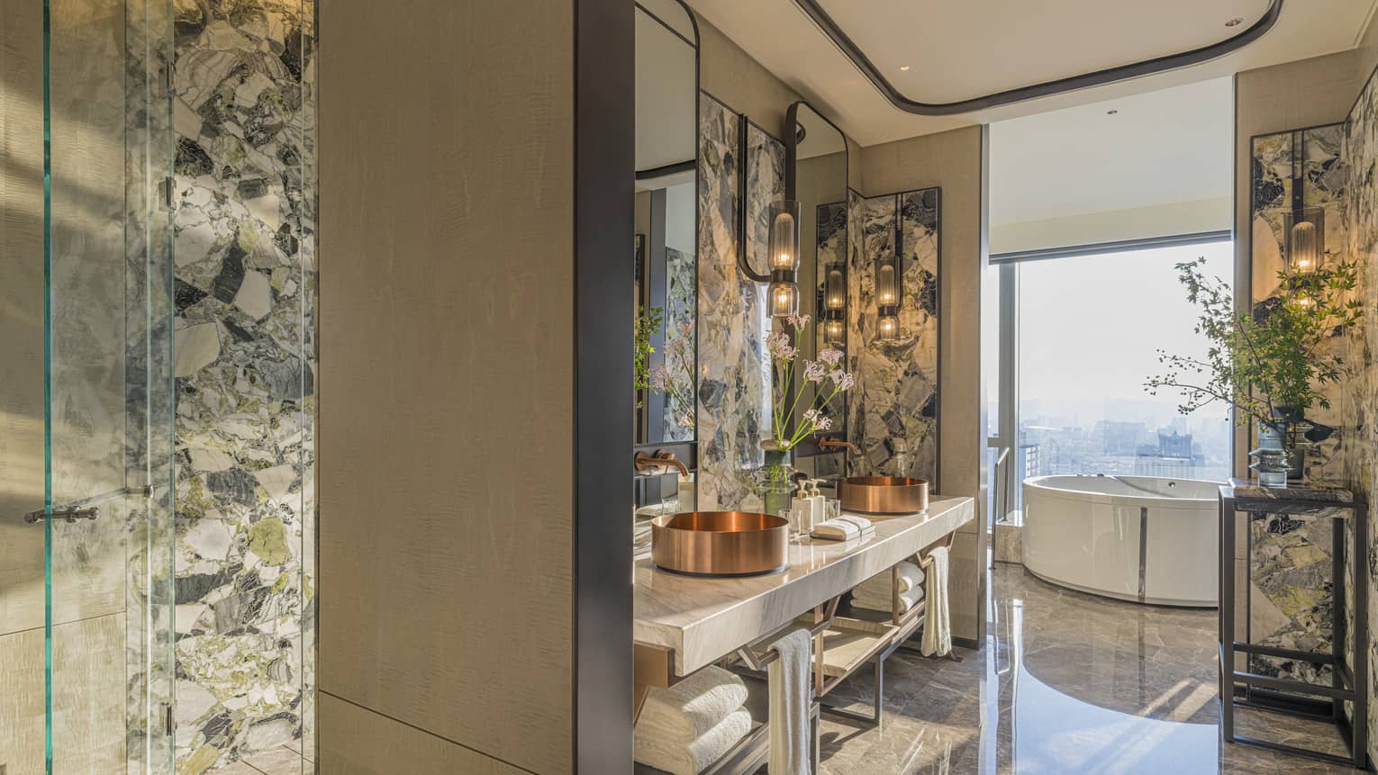 Entryway into a luxury suite bathroom with glass wall next to standalone tub, overlooking city