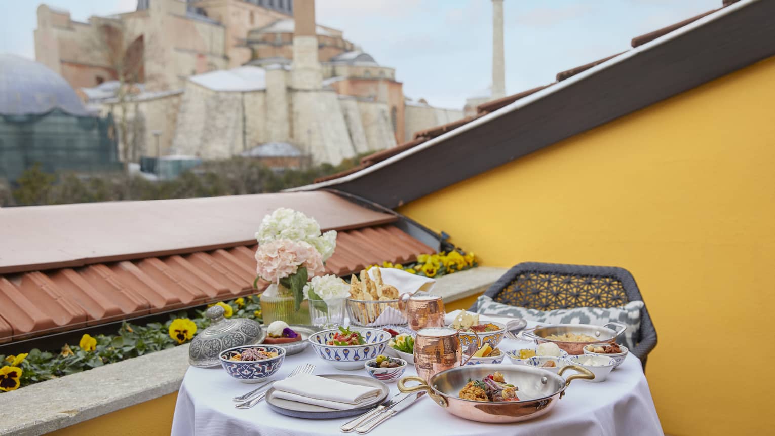 Round table set for in-room meal on terrace with view of mosque