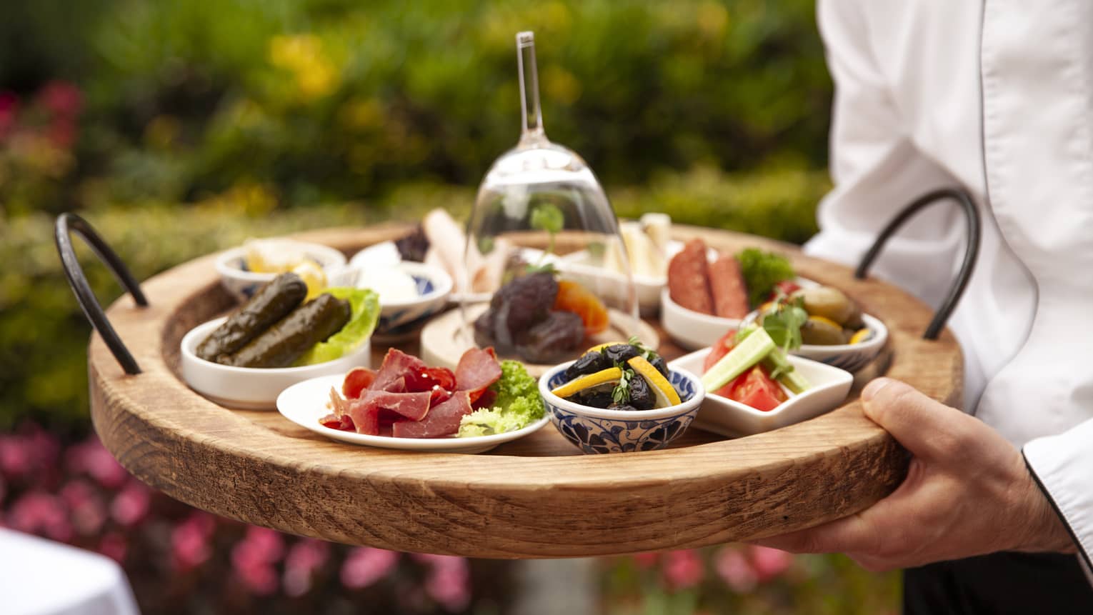 Server carrying wooden tray of Ramadan small plates