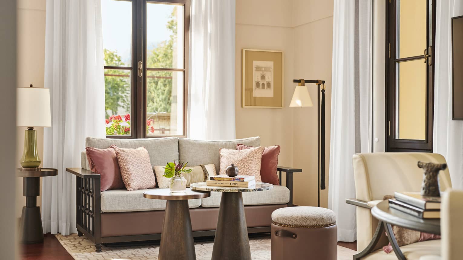 A hotel guest room with a small sofa, coffee table and large window.