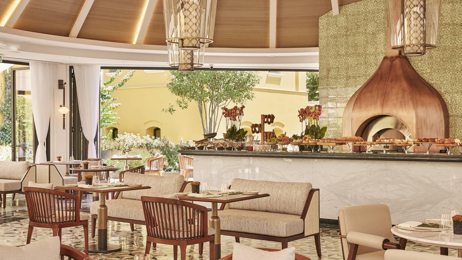 A dining outlet with a large counter area with many small tables near it.