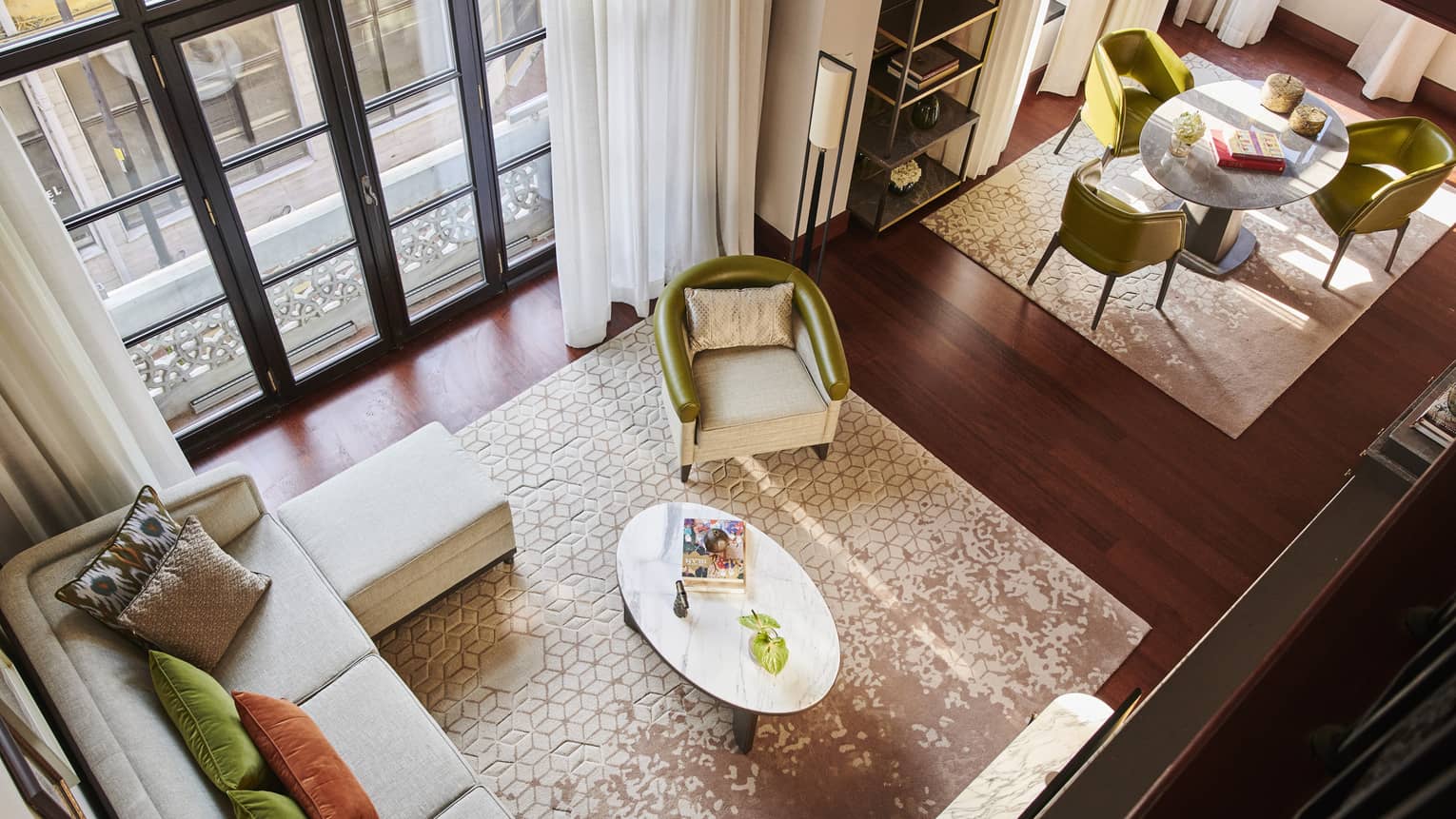 Aerial view of Hotel suite with neutral living room, tall windows and contemporary round dining set