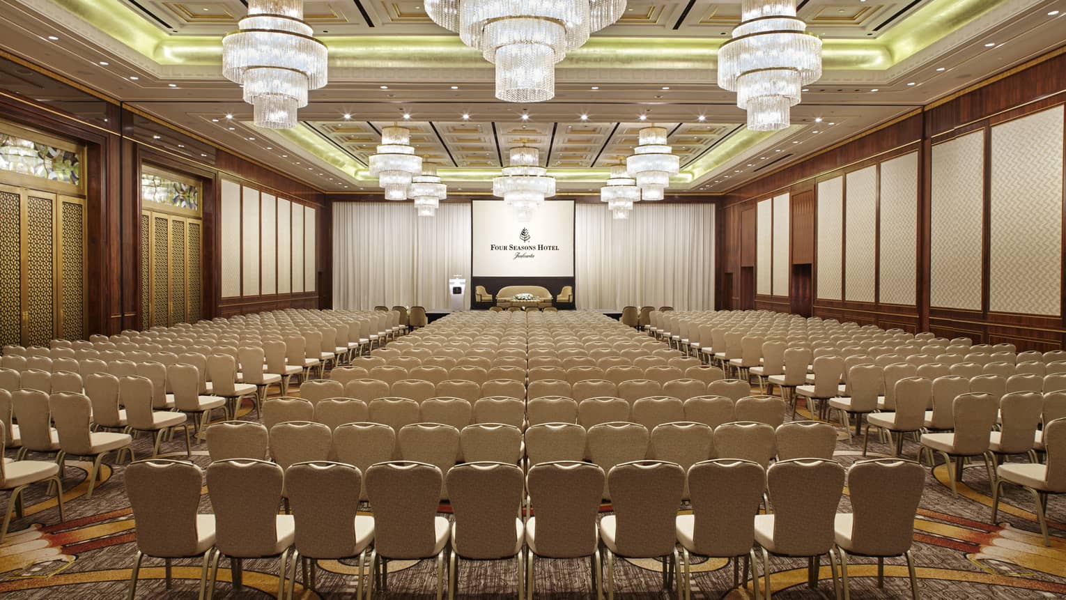 Meeting chairs in rows facing screen with Four Seasons Hotels logo for conference set up in Grand Ballroom