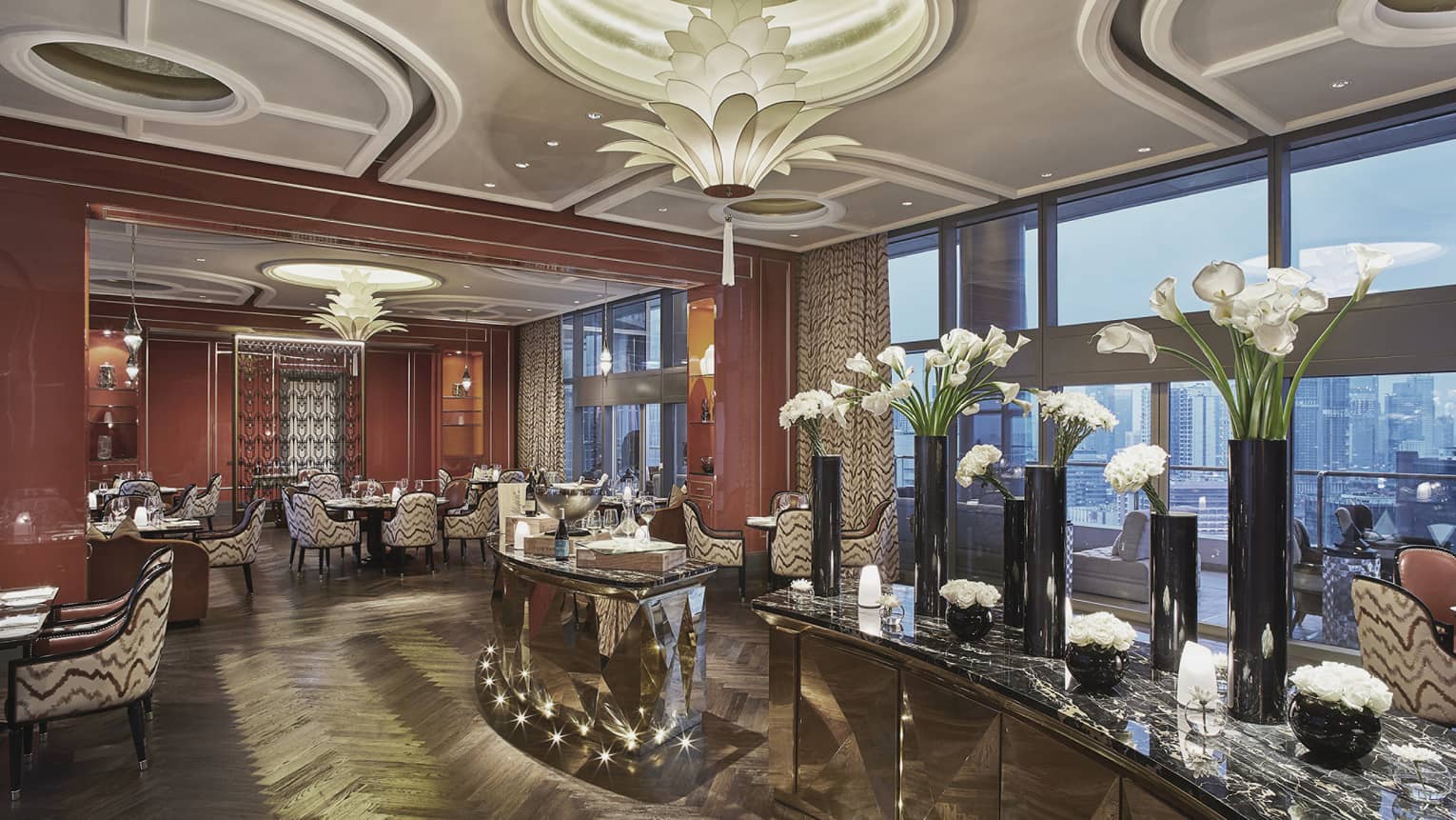An elegant restaurant decorated with white flowers in vases of varying sizes and a wine display in the middle of the room.