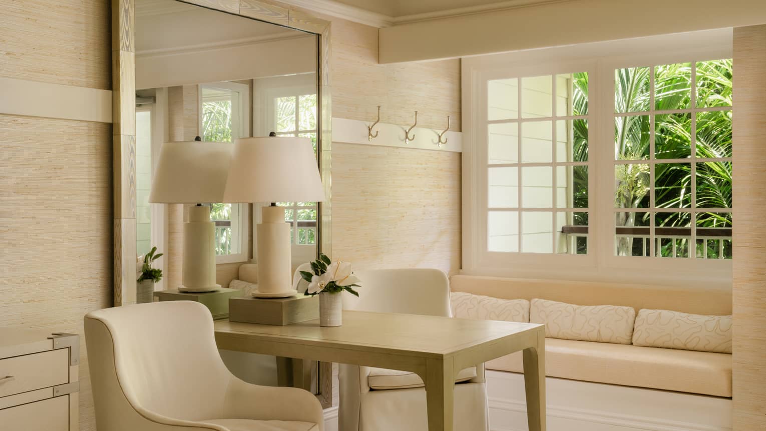 Luxury room at tropical resort, featuring fresh, off-white furnishings including a table and two chairs