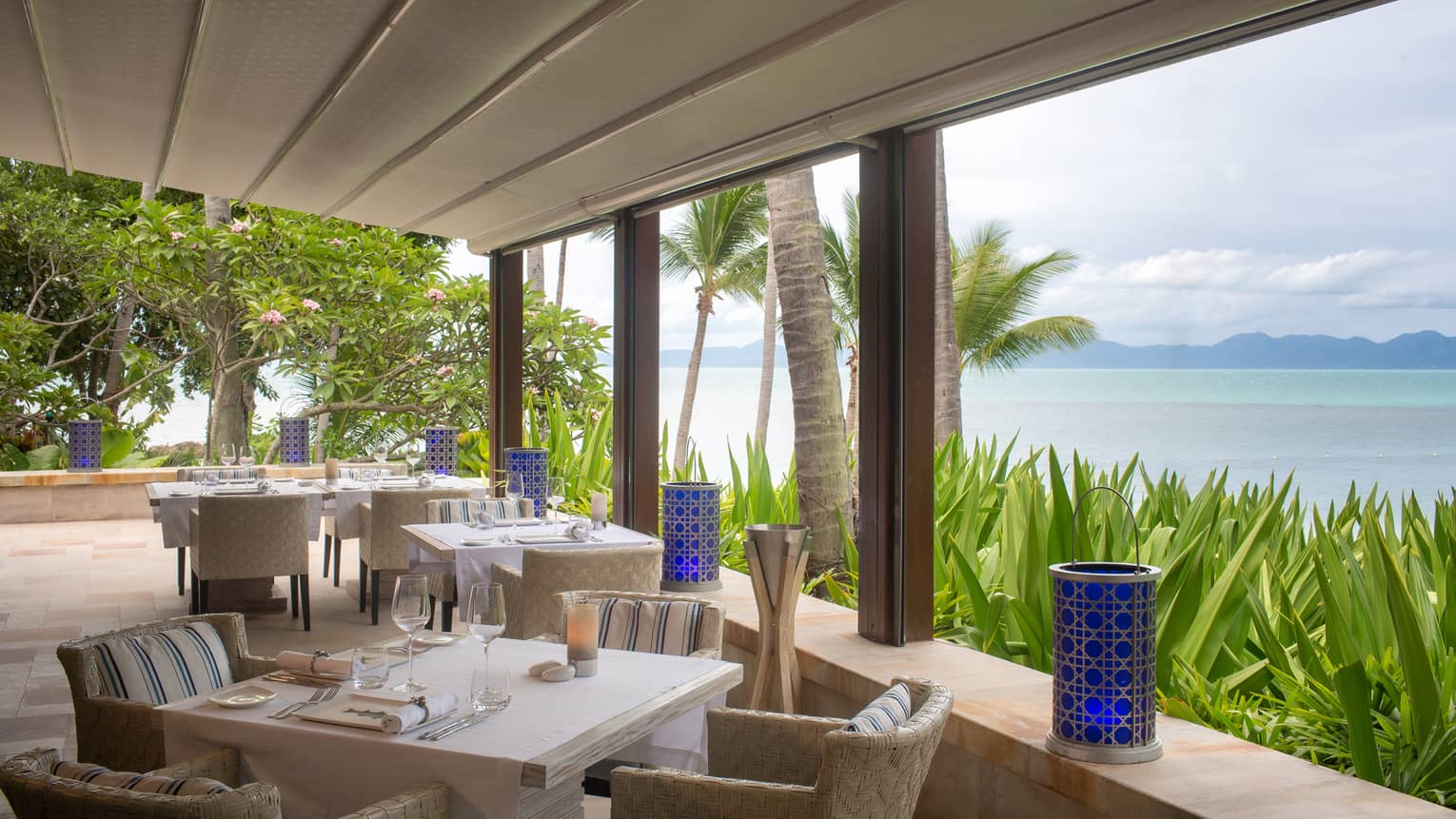 square tables overlooking the ocean are set for dinner
