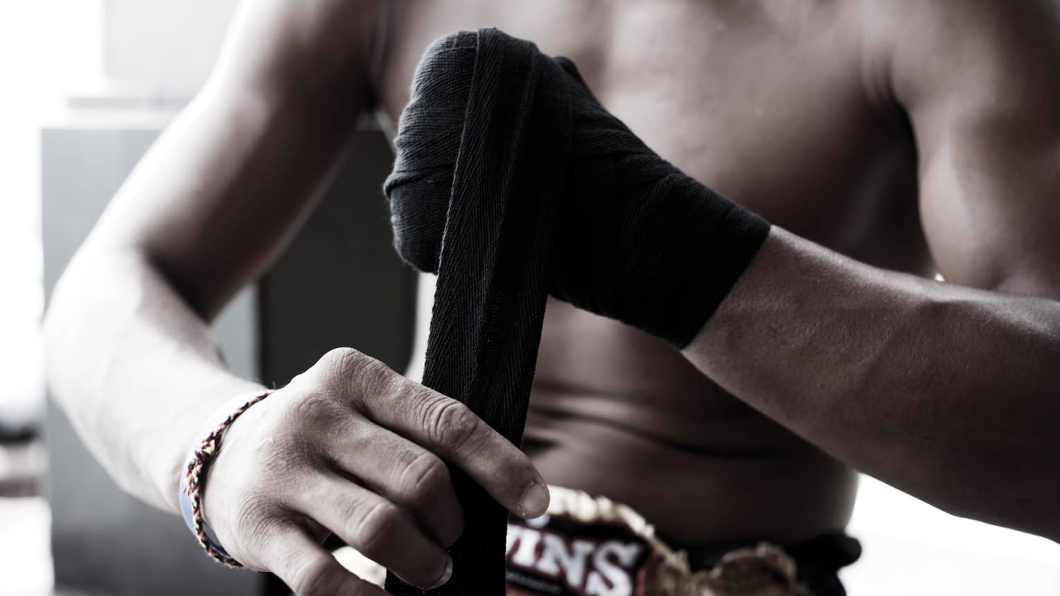 Close-up of Muay Thai boxer wrapping black boxing tape around hands