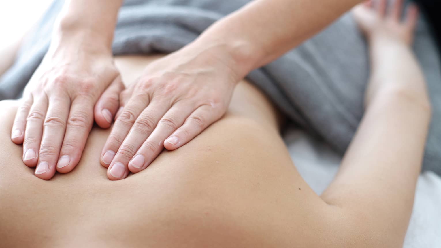Hands massaging bare shoulders, back