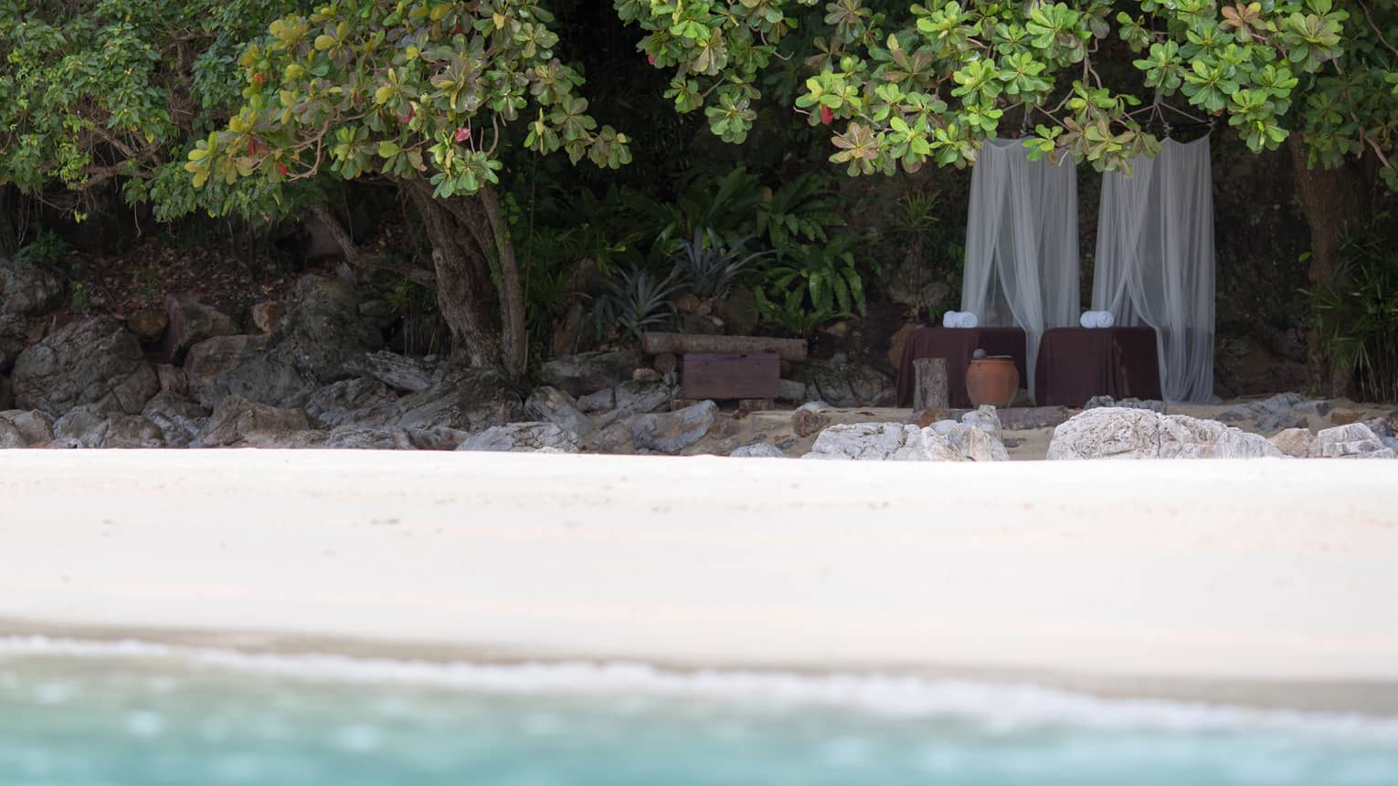 White canopy nets over spa beds in mountain by white sand beach