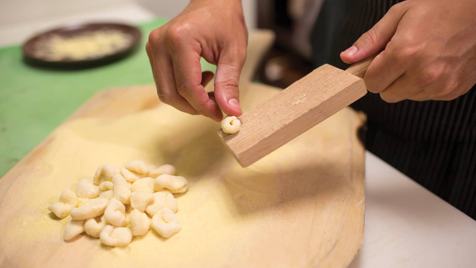 Close-up of chef's hands making fresh gnocchi over wood board