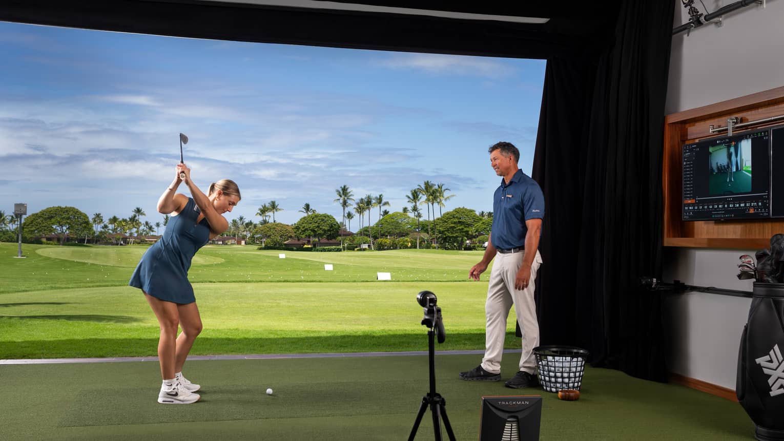 A woman practices her golf swing in an indoor simulator setting.